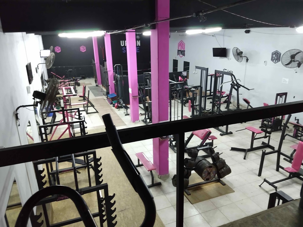 Fachada nocturna con hexágono neón fucsia de Pro Gym Paraná en esquina céntrica