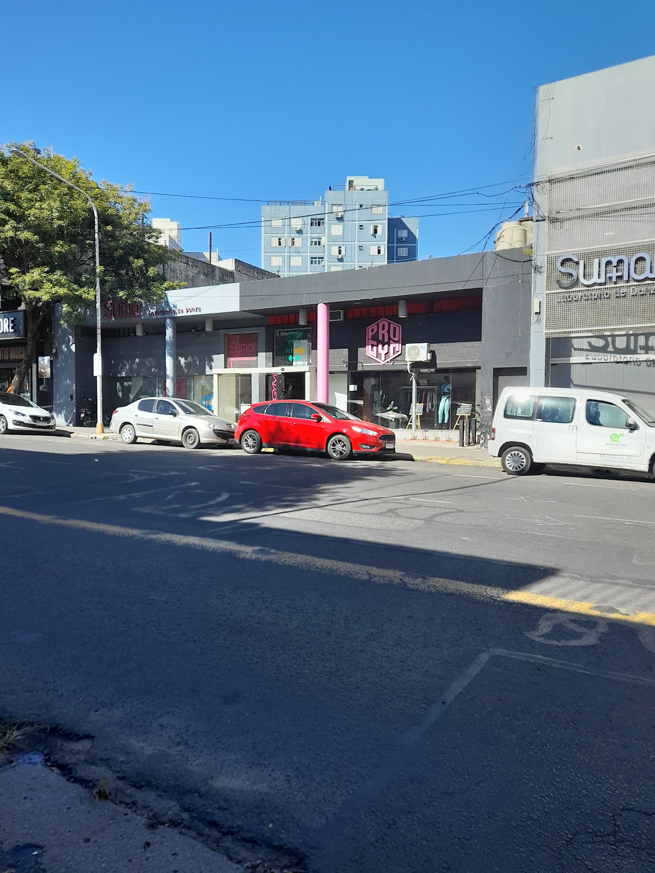 Sala de musculación con luces neón fucsia y violeta, racks de mancuernas pesadas y barras de fuerza