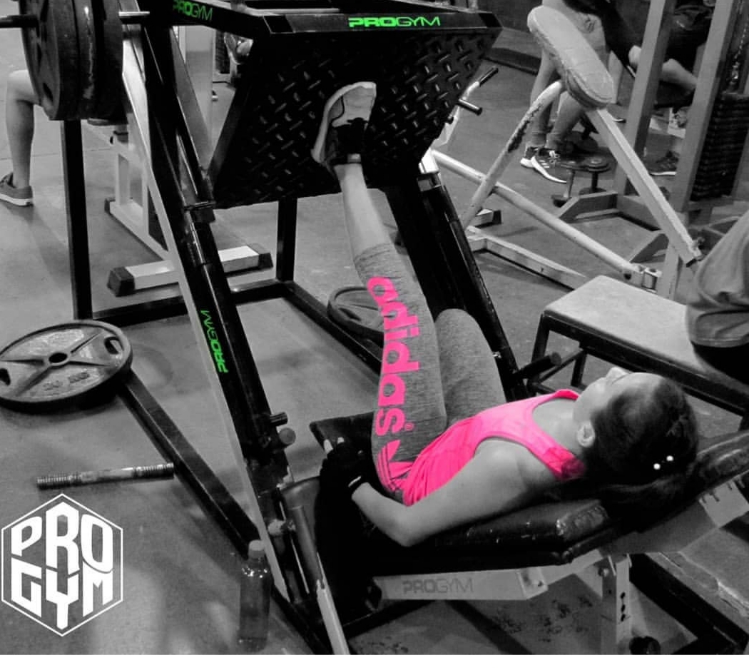 Sector de cardio con hileras de cintas de correr y remos con iluminación violeta intensa